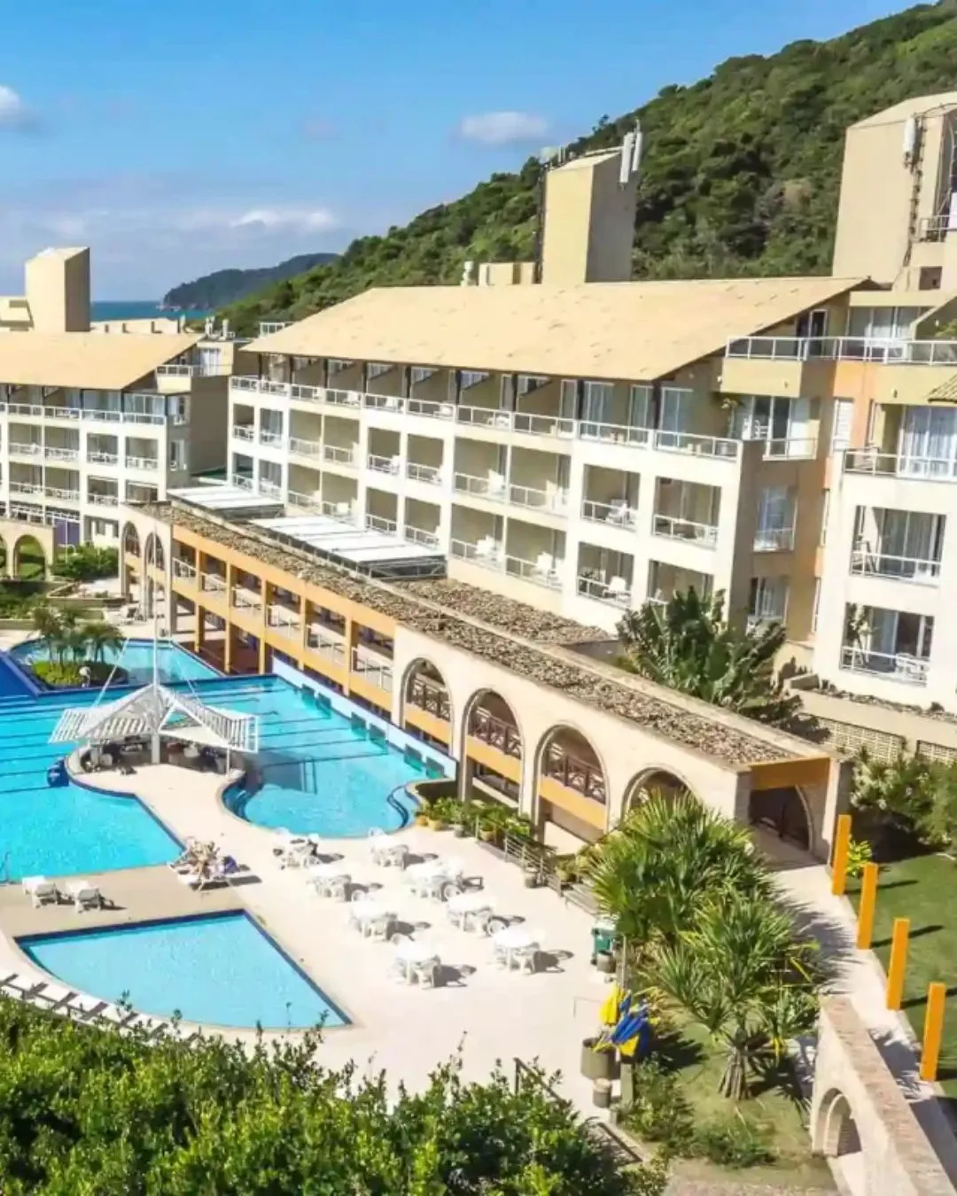 Como funciona o RCI viagens? Guia completo para transformar sua propriedade de férias em experiências incríveis 6 Uma vista aérea de um grande resort com uma piscina ao ar livre e o mar ao fundo. Entenda como funciona o RCI viagens para planejar suas férias em família.