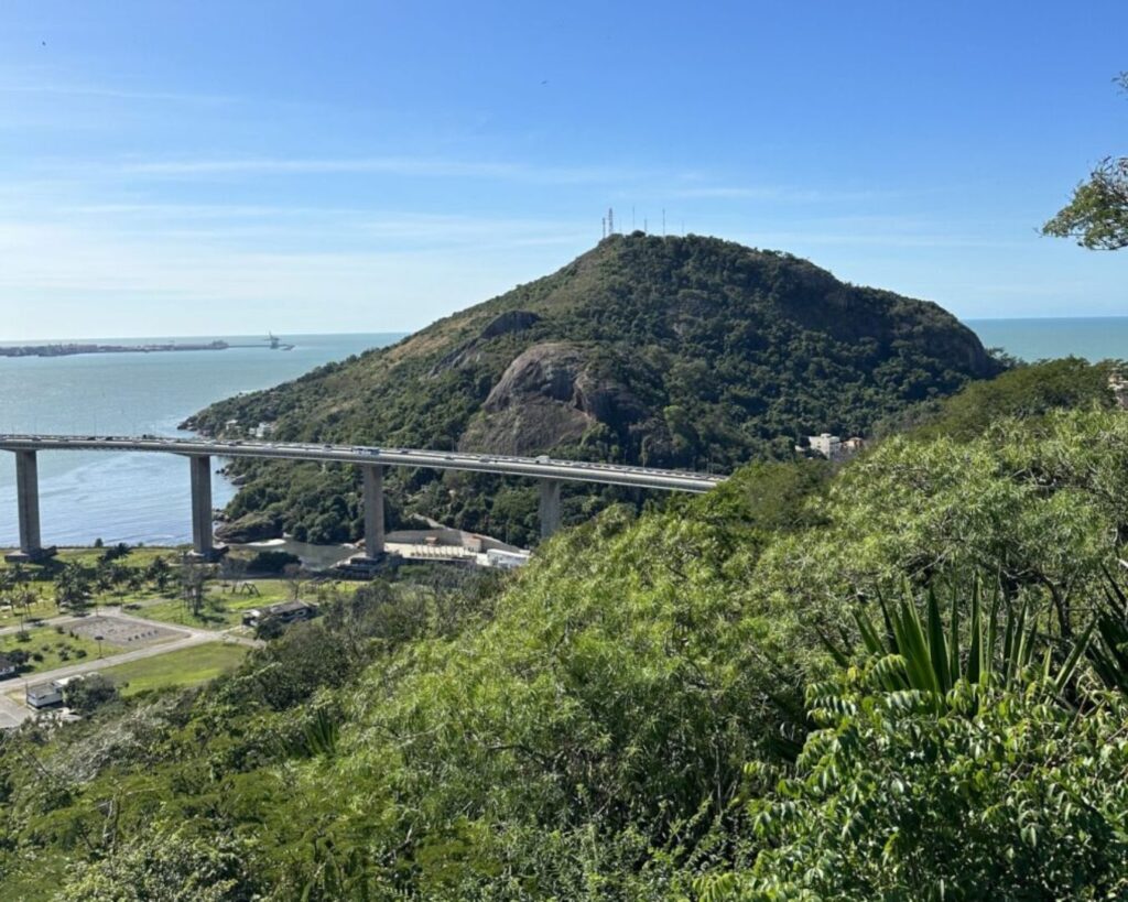 Morro do Moreno: Um guia completo para trilhas, atividades e o nascer do sol 1 Uma imagem icônica e de alta resolução do Morro do Moreno visto de longe, talvez da Praia da Costa ou da Terceira Ponte, para contextualizar o leitor