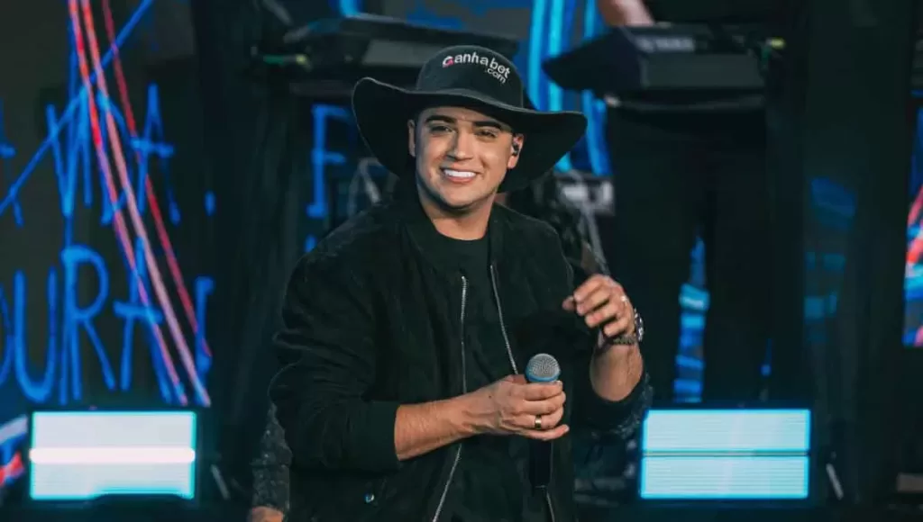 Foto de Natanzinho Lima cantando em seu show na Expo Aracruz 2025. O cantor segura o microfone e interage com o público, destacando a energia do show do Natanzinho Lima em Aracruz.