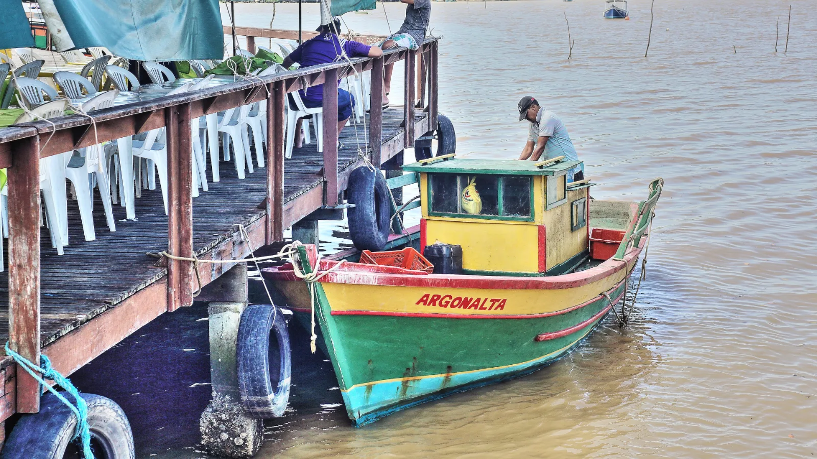 Casas de palafita e barco de pesca colorido na orla da Ilha das Caieiras, em Vitória (ES)