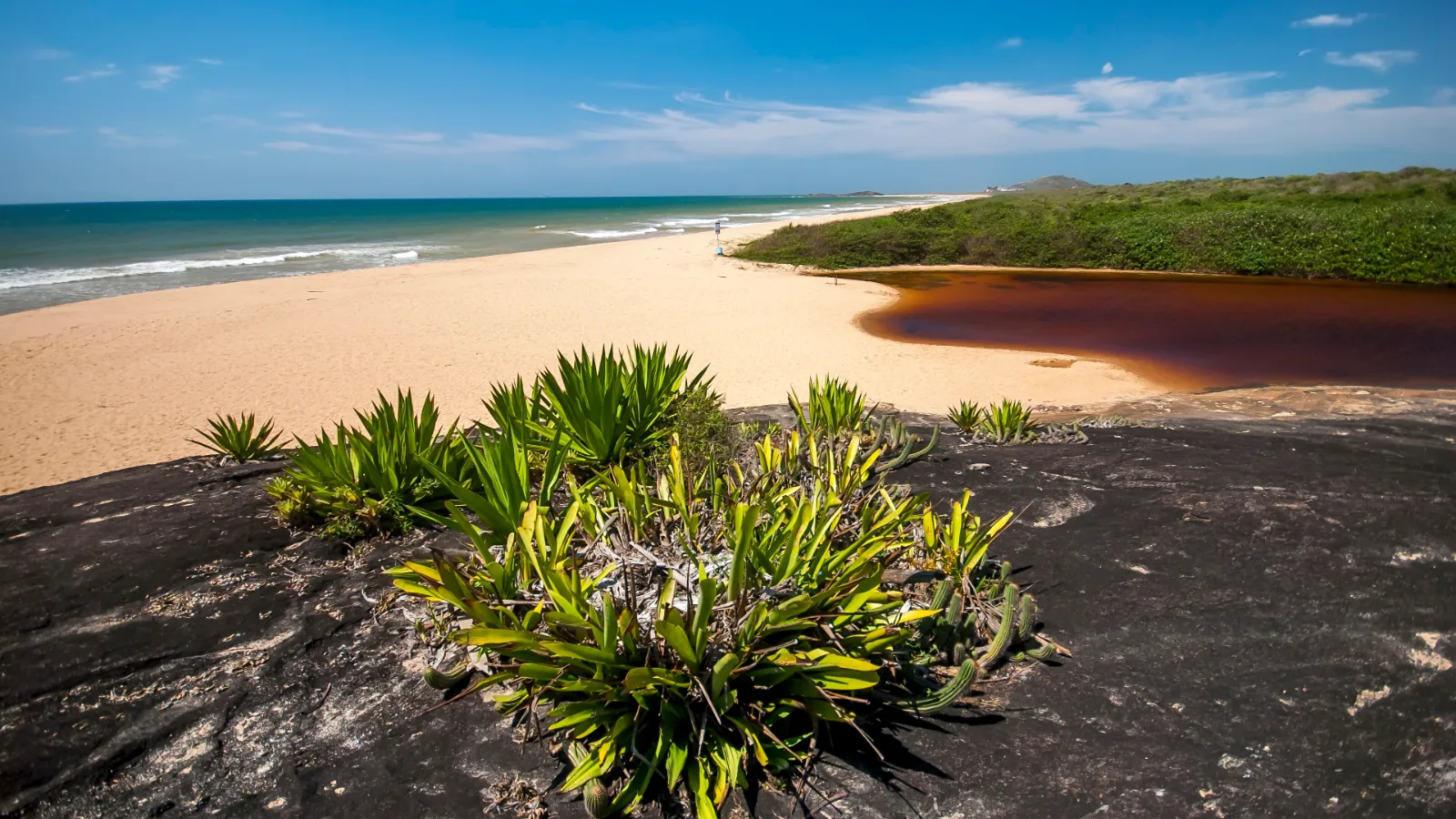 Lagoa de Caraís, de águas escuras e avermelhadas, em frente à praia