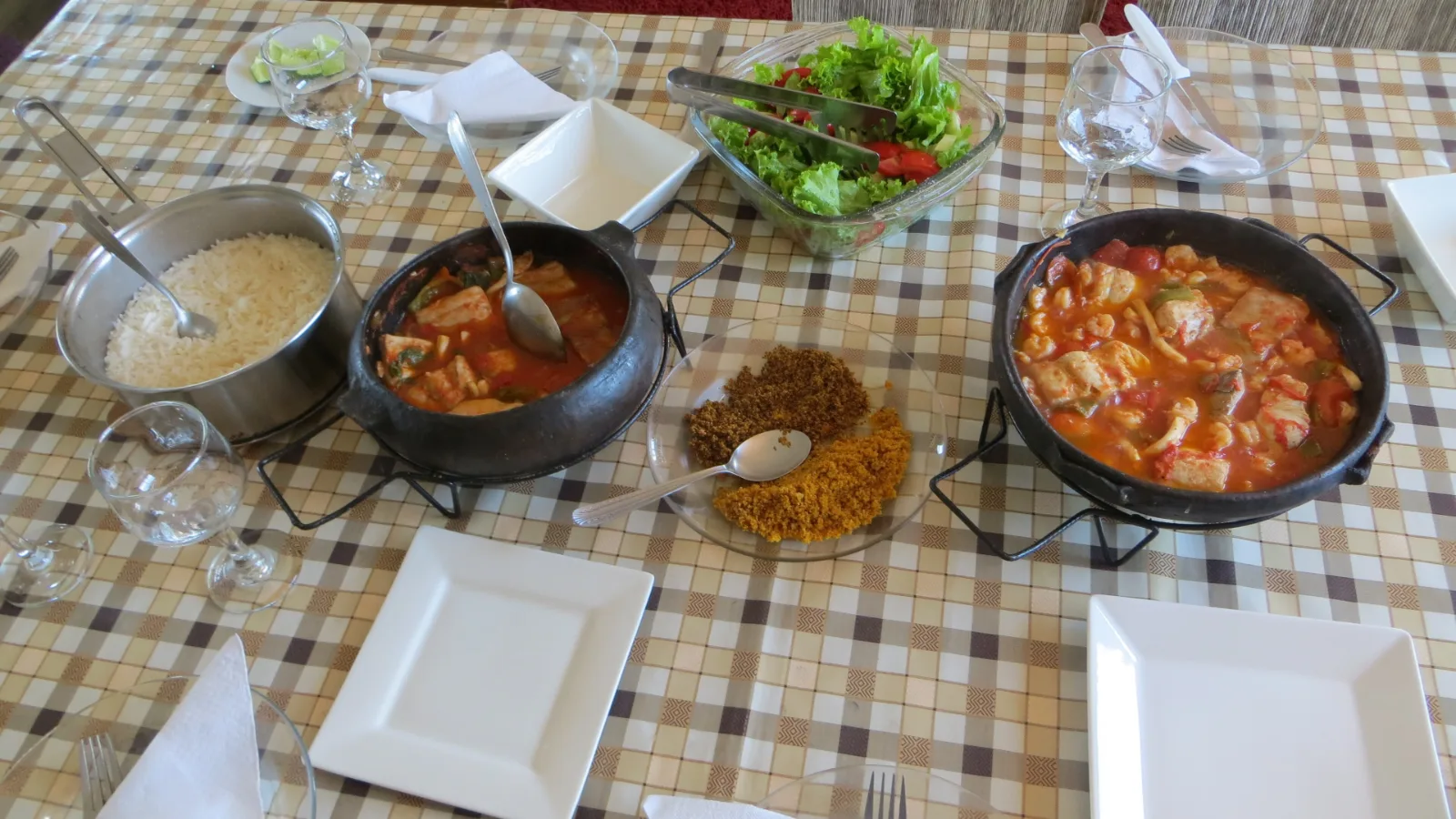 Mesa com moqueca capixaba, pirão e acompanhamentos