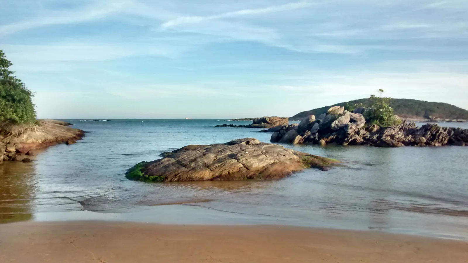 Águas cristalinas e piscinas naturais entre rochas na Praia de Peracanga